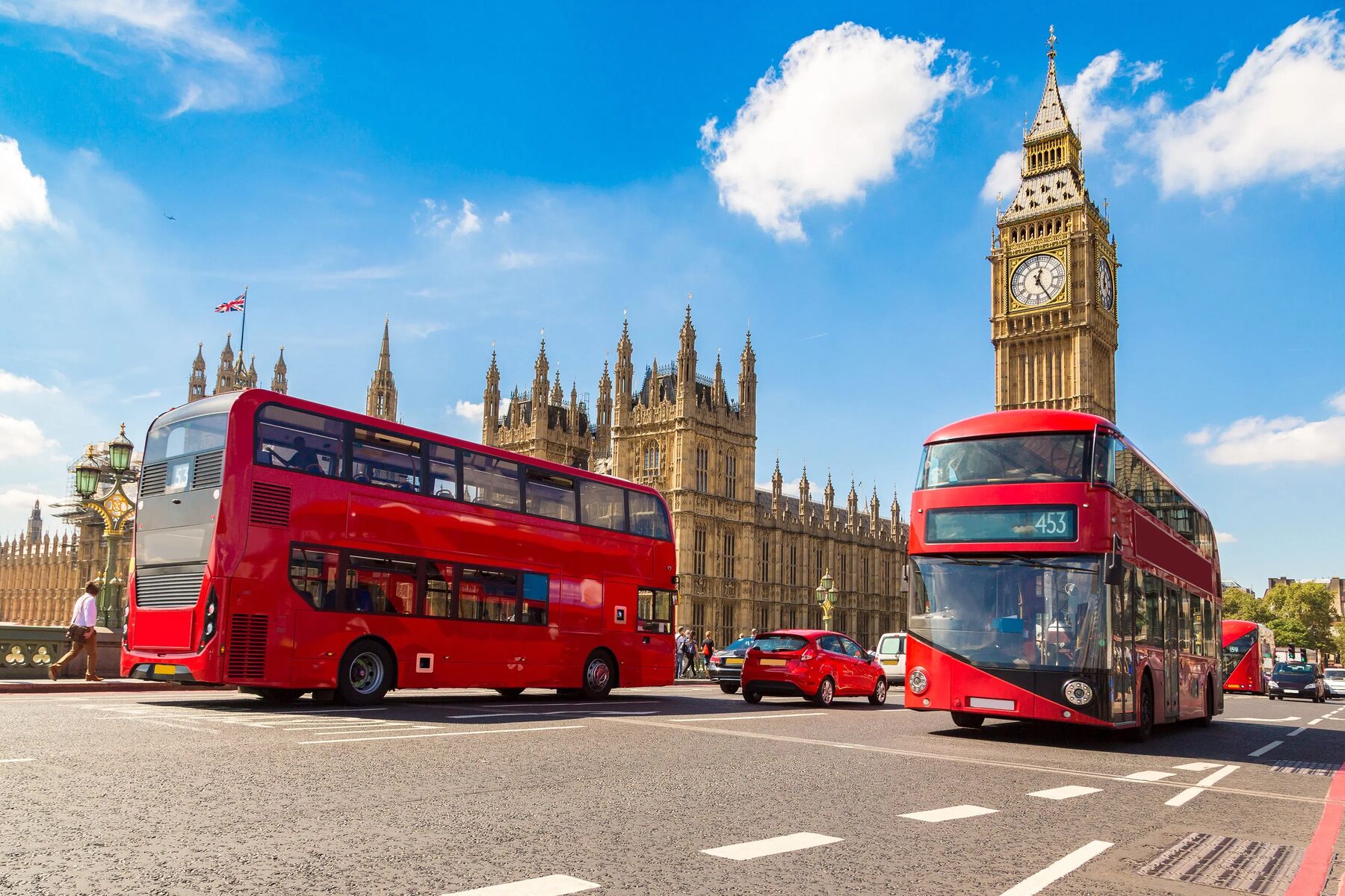 Red double-decker buses passing Big Ben and the Houses of Parliament in London